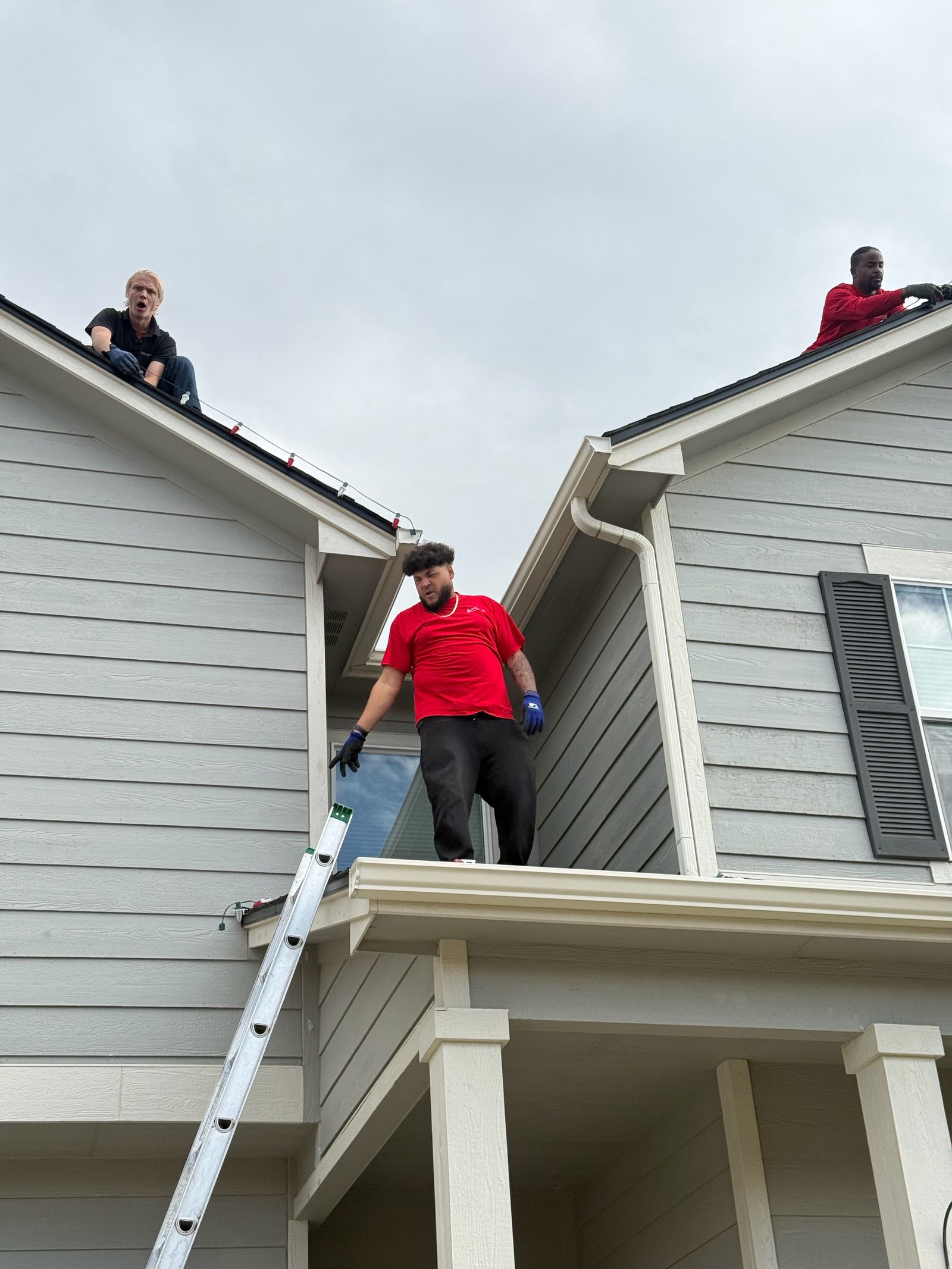 Our team installing multicolor Christmas lights along roof peaks