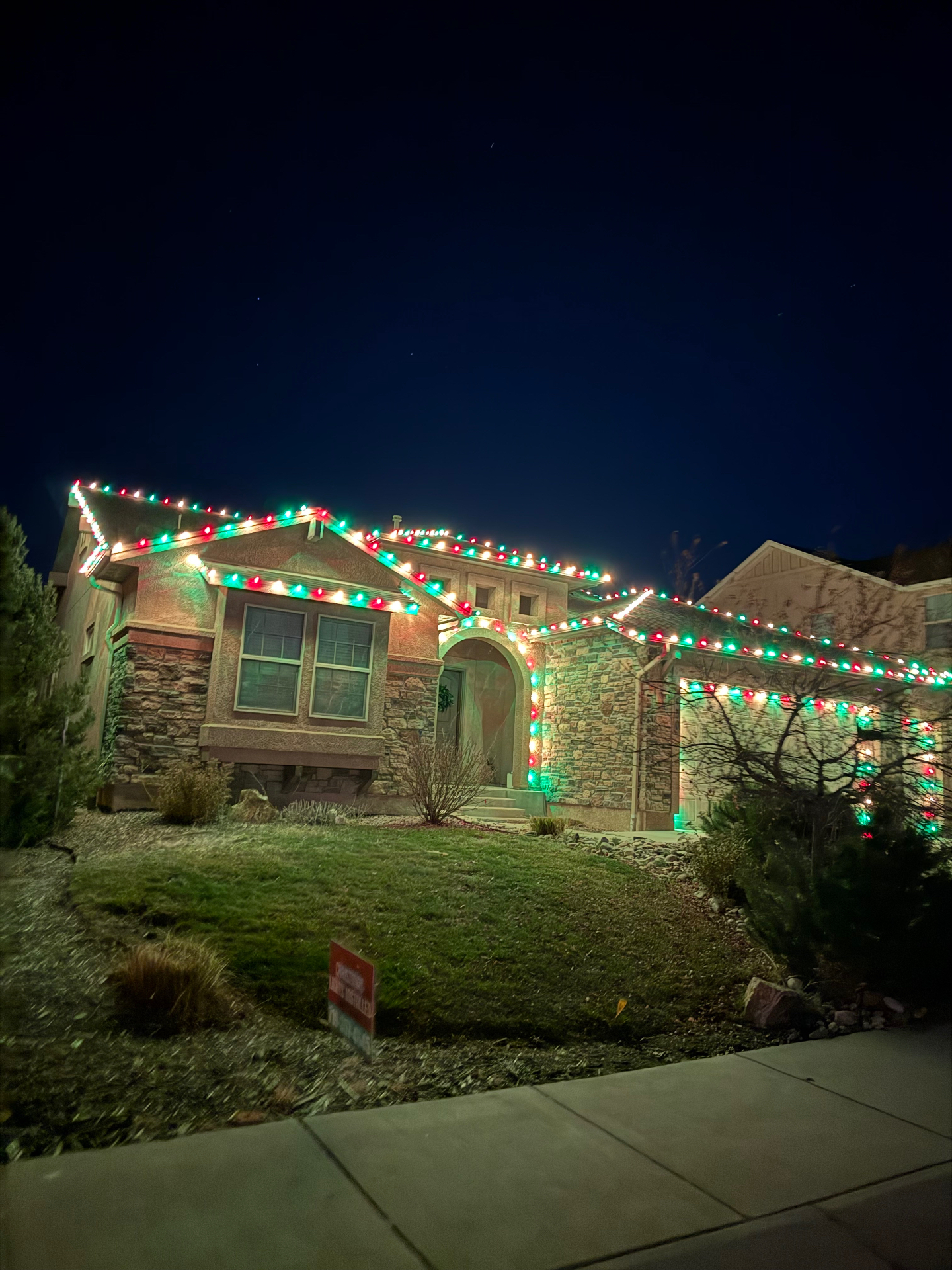 Multicolor holiday display Multicolor Christmas lights on a two-story Front Range home with roofline and landscape holiday lighting